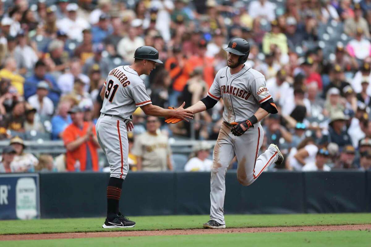 San Francisco Giants' Austin Slater, right, is congratulated by third base coach Mark Hallberg as he rounds the bases after hitting a solo home run against the San Diego Padres in the seventh inning of a baseball game Wednesday, Oct. 5, 2022, in San Diego. (AP Photo/Derrick Tuskan)