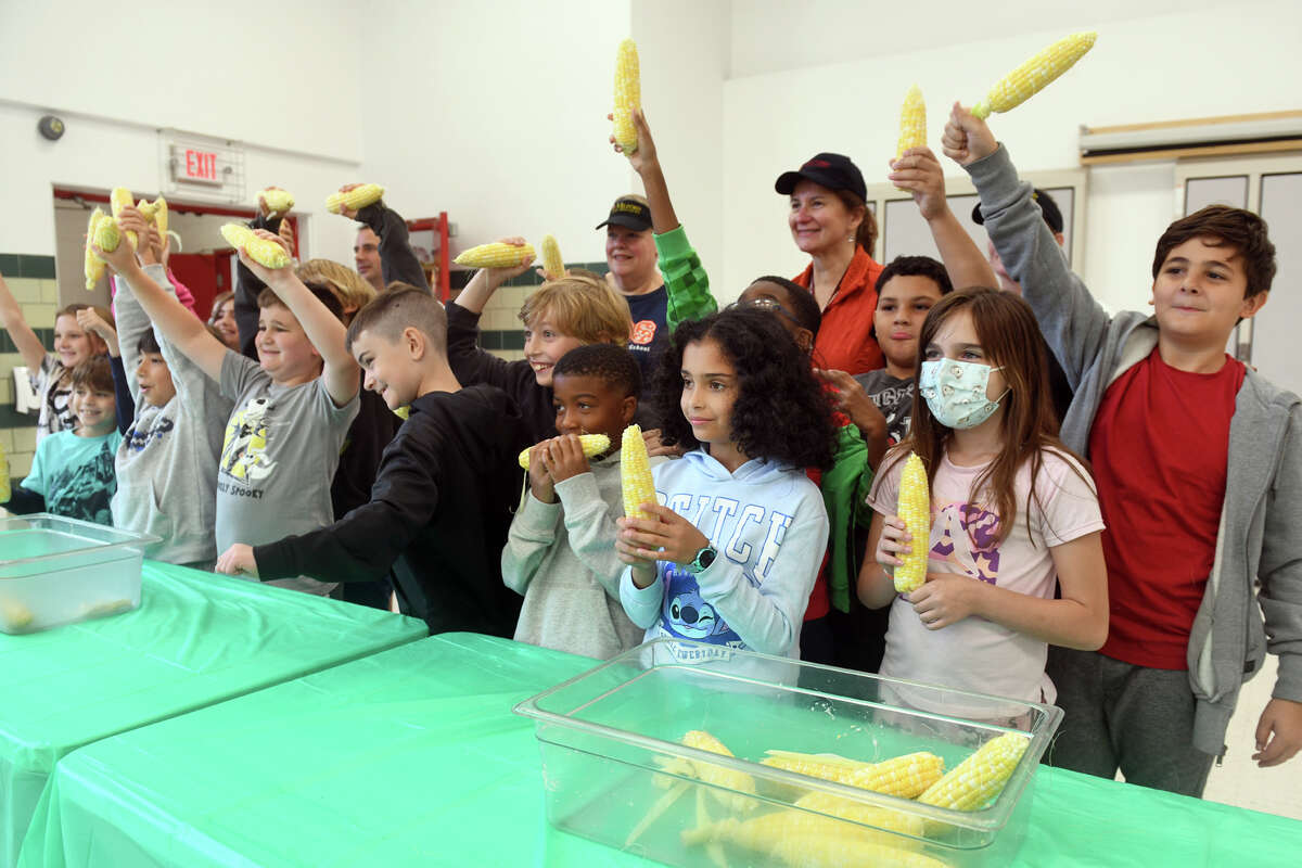 Fourth-grade student pose with earns of corn following a corn shucking competition at Pumpkin Delight Elementary School, in Milford, Conn. Oct. 4, 2022.