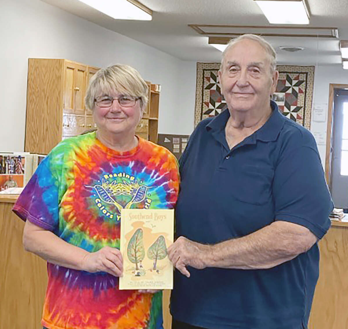 Dr. Thomas Newman (right) presents a copy of his book, “Southend Boys,” to Janet Wells, librarian at M-C River Valley Library in Meredosia. Newman’s book is a collection of stories recalling his childhood adventures with his friends, the Southend Boys, in small-town Meredosia.