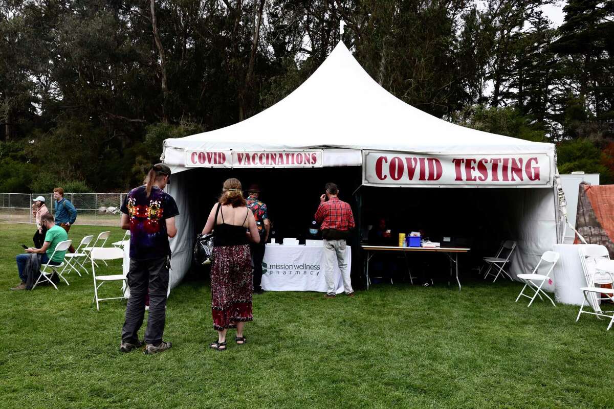 People stand in line at the COVID-19 vaccination tent near the Bandwagon Stage during the Hardly Strictly Bluegrass Festival at Golden Gate Park in San Francisco on Oct. 1, 2022. The music festival returned following a two-year hiatus due to the pandemic.