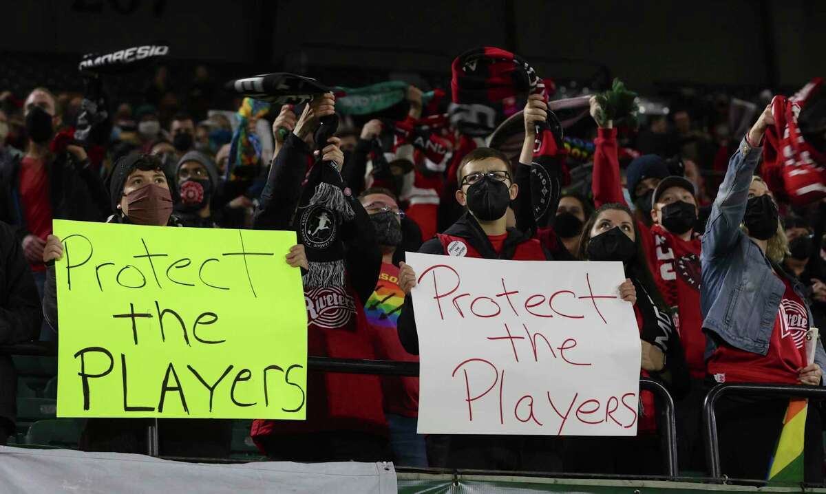 FILE - Portland Thorns fans hold signs during the first half of the team's NWSL soccer match against the Houston Dash in Portland, Ore., Wednesday, Oct. 6, 2021. An independent investigation into the scandals that erupted in the National Women's Soccer League last season found emotional abuse and sexual misconduct were systemic in the sport, impacting multiple teams, coaches and players, according to a report released Monday, Oct. 3, 2022. (AP Photo/Steve Dipaola, File)