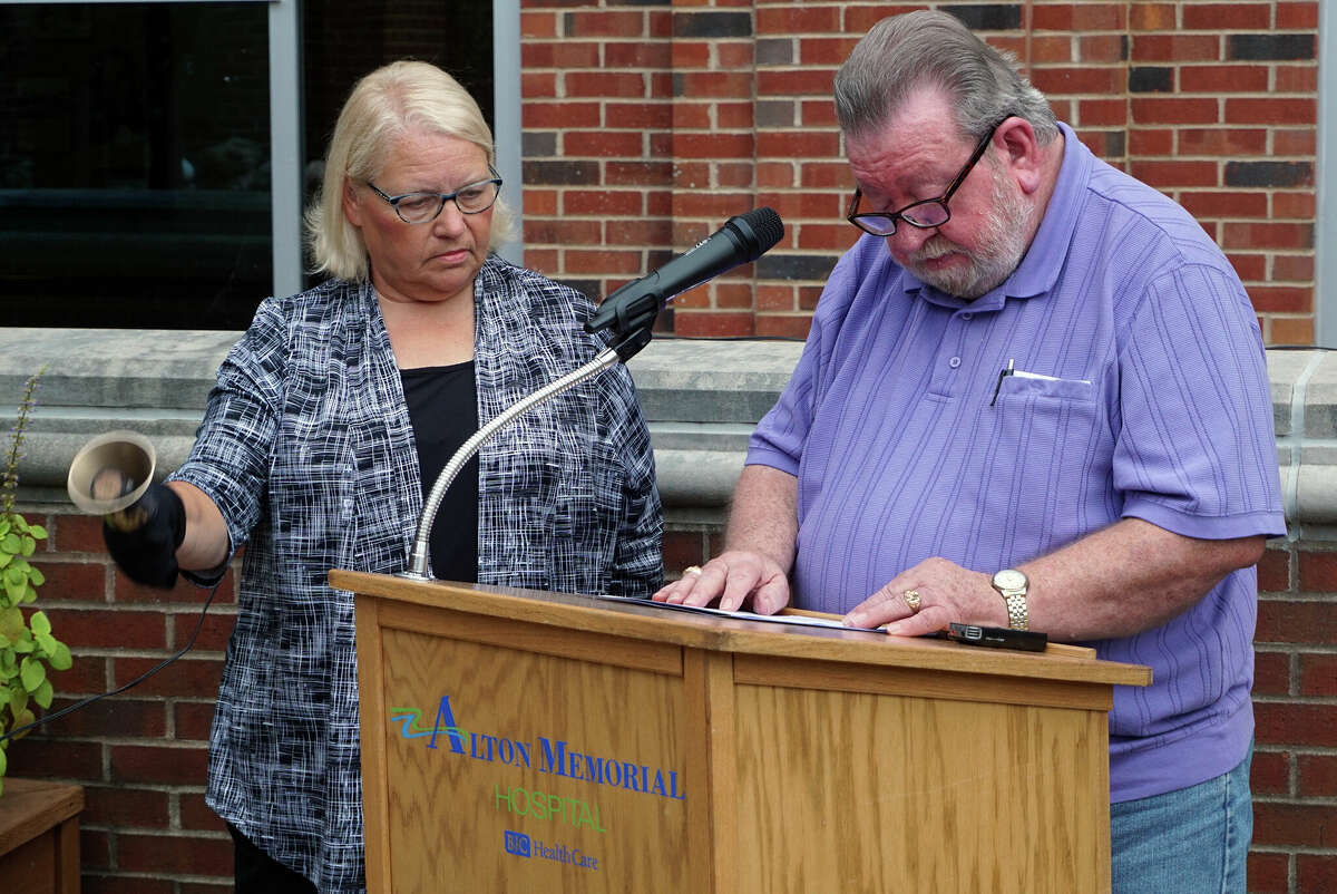 Cindy Kirbach of Upper Alton Baptist Church rings bells as Bob Vandalia of the Community Faith Committee reads the names of domestic violence victims during the 2019 remembrance event at Alton Memorial Hospital.