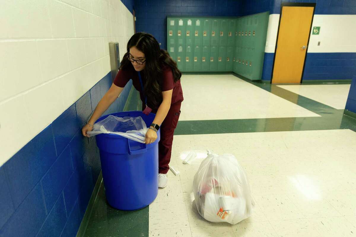 Julia Reyes changes a trash bag in a MacArthur High School hallway on Thursday as part of an 8-year-old program that helps custodians keep their school clean — now a necessity rather than a good will gesture, because of a severe custodian shortage throughout NEISD. Students at other schools are also stepping up.