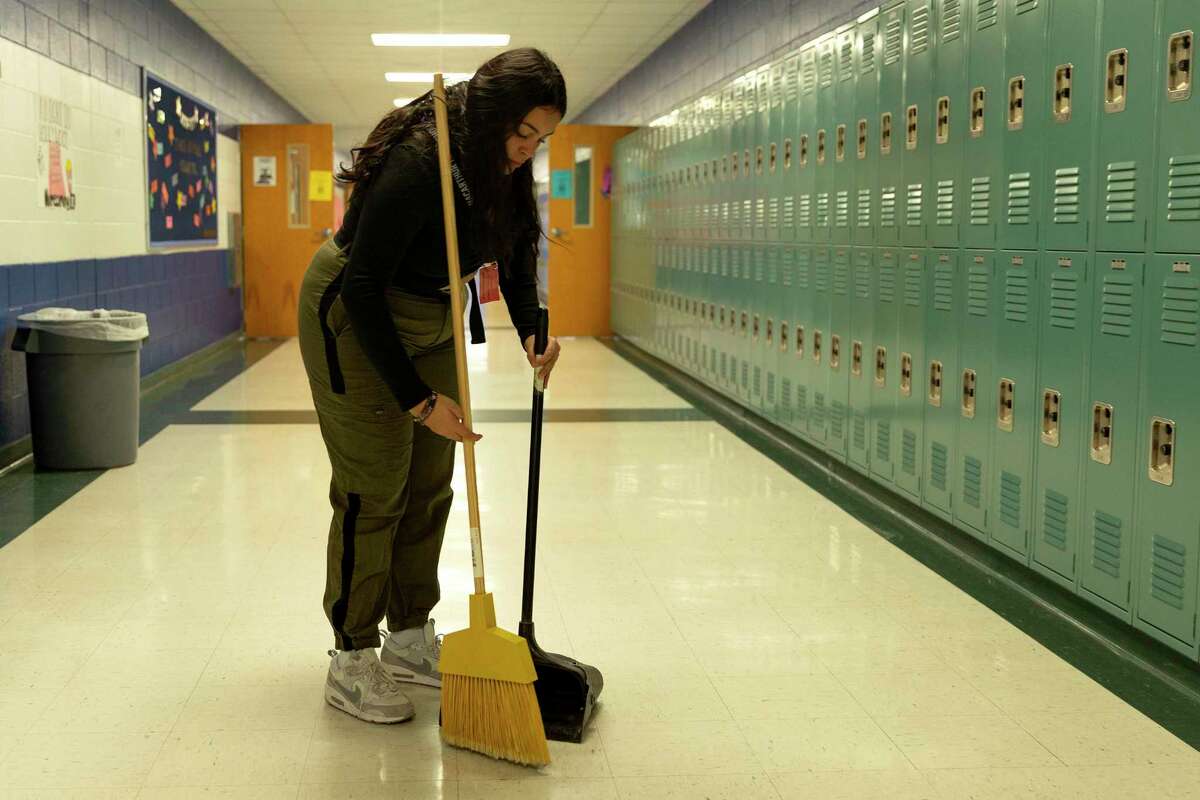 Brisa Rico sweeps a second floor hallway at MacArthur High School on Thursday, part of a program that helps keep the school clean — now a necessity rather than a good will gesture, because of a severe custodian shortage throughout NEISD. Each afternoon around 15 students sweep and change trash bags, saving hours of work for two custodians.
