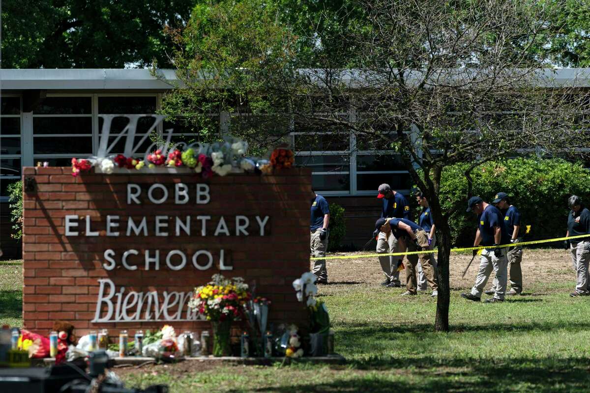 FILE - Investigators search for evidences outside Robb Elementary School in Uvalde, Texas, May 25, 2022, after an 18-year-old gunman killed 19 students and two teachers. Four months after the Robb Elementary School shooting, the Uvalde school district on Friday, Oct. 7 pulled its entire embattled campus police force off the job following a wave of new outrage over the hiring of a former Texas state trooper who was part of the hesitant law enforcement response as a gunman killed 19 children and two teachers.