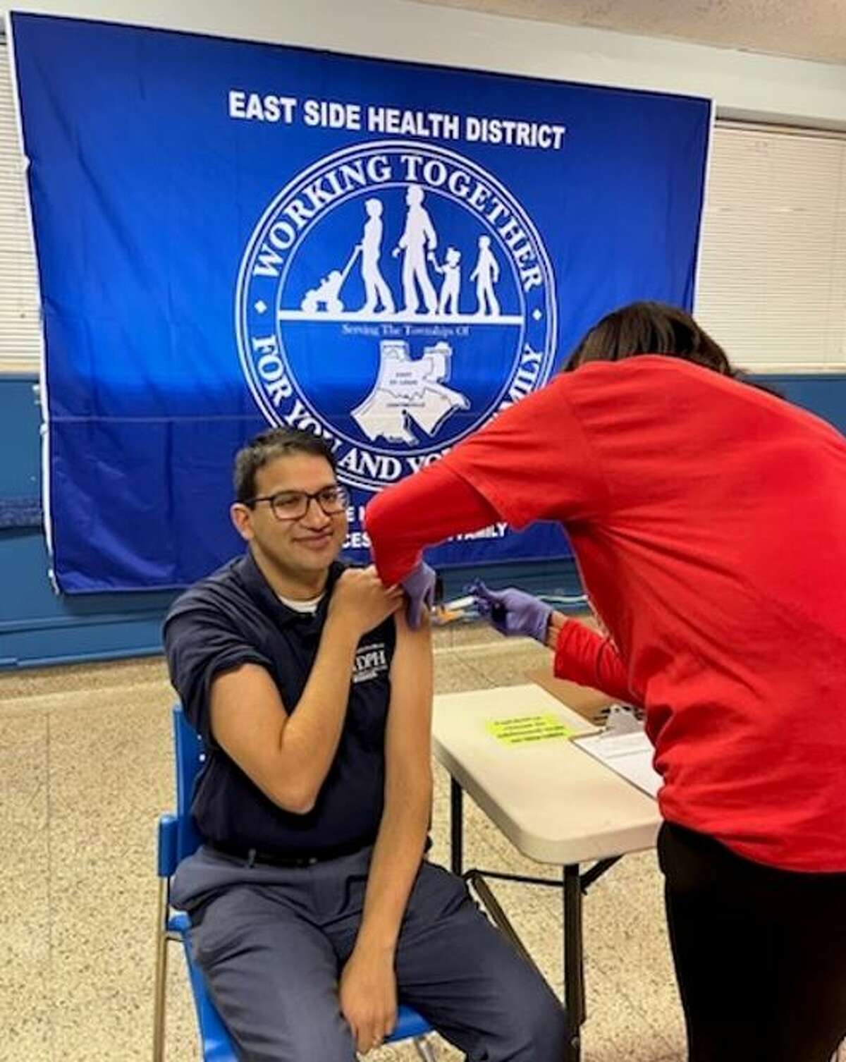 Illinois Departmtne of Public Health Director Dr. Sameer Vohra receives a Covid booster shot from Angela Clark, RN, the head nurse at the East Side Health District in East St. Louis, on Friday.