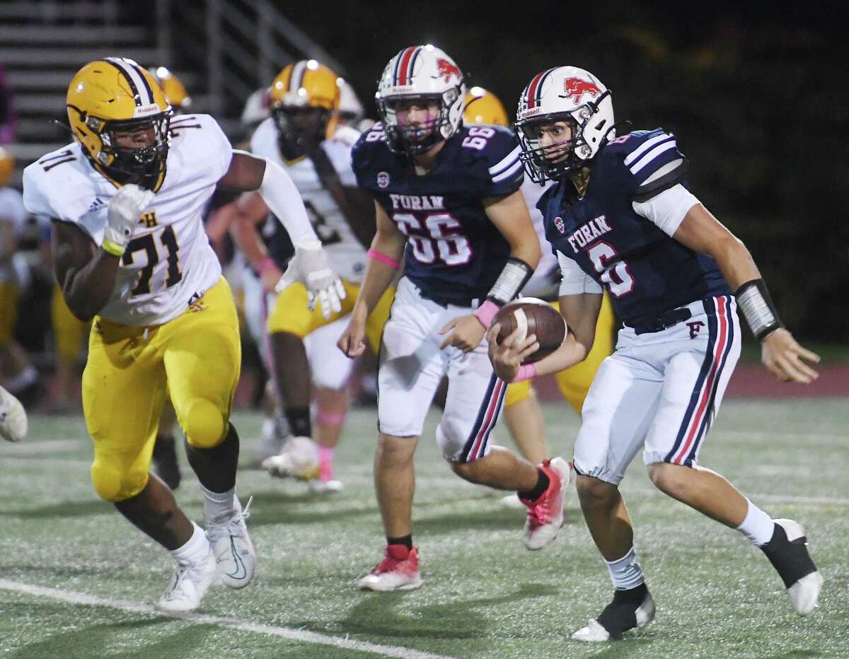 Foran quarterback Jack Cushman makes yards up the middlle pursued by East Haven's Mekhi Morrison during the first half of their football game at Foran High School in Milford, Conn. on Friday, October 7, 2022.