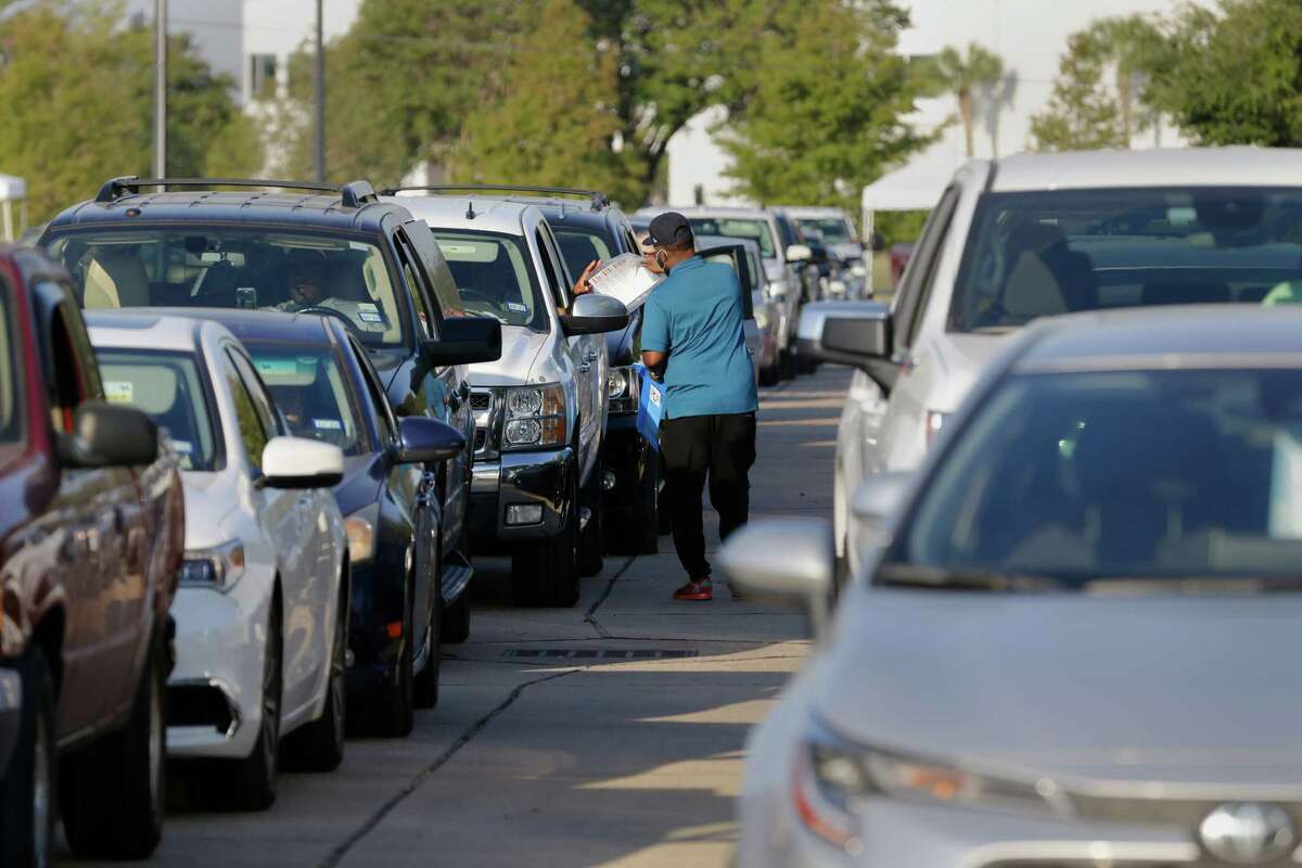 Some 300 cars waiting in line to drop off guns are handed paperwork as they wait during the second gun buy back program, held at the Metro Westchase Park and Ride location Saturday, Oct. 8, 2022 in Houston, TX.