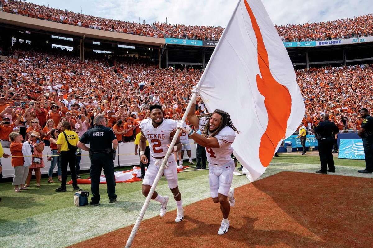 Texas wide receiver Jordan Whittington (4) and running back Roschon Johnson (2) celebrate with the Texas Longhorns flag after their team's 49-0 victory over Oklahoma in an NCAA college football game at the Cotton Bowl, Saturday, Oct. 8, 2022, in Dallas. (AP Photo/Jeffrey McWhorter)