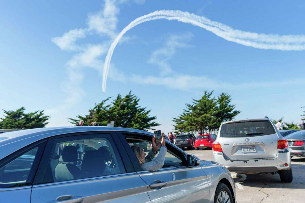 2022年10月8日，在美国加利福尼亚州旧金山，一名女子在她的车里拍摄“蓝天使”在科伊特塔上空飞行
