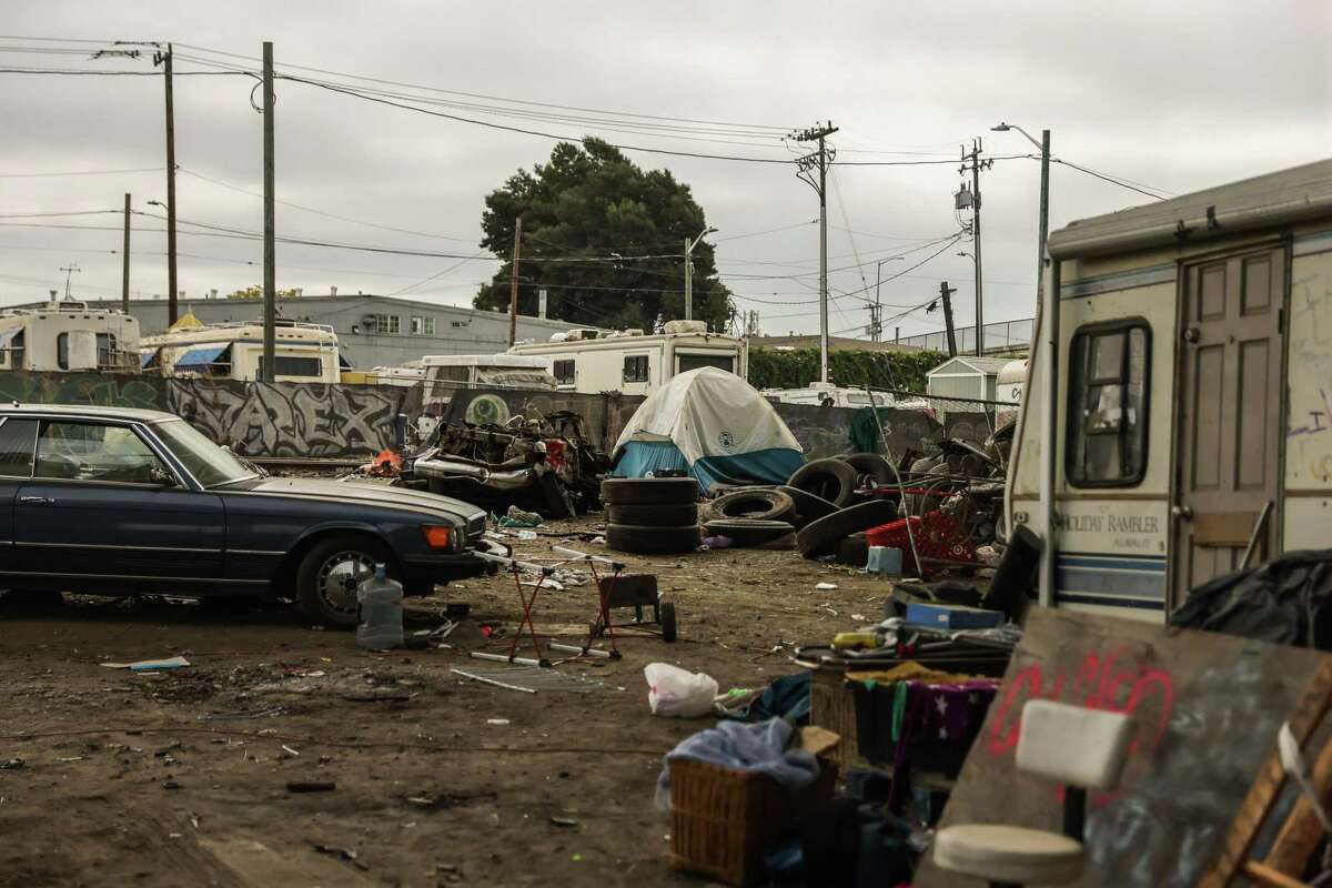 A tent is pitched amid trash and cars at the Wood Street encampment in Oakland.