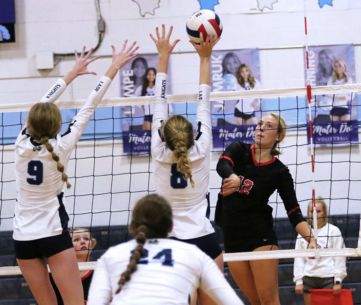 Staunton's Haris Legendre (right) hits off the block by Breese Mater Dei's Addie Nenninger (8) with the Knights' Elyse Strader (9) also contesting the attack in a Sept. 13 match in Breese. On Saturday, Legendre made Macoupin County All-Tourney for the third time in three seasons while leading the Bulldogs to a fifth straight county title.
