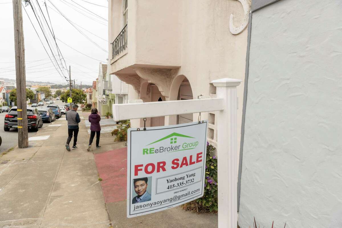 People walk past a sale sign for a home in San Francsico, Calif., on Wednesday, Jun 29, 2022.