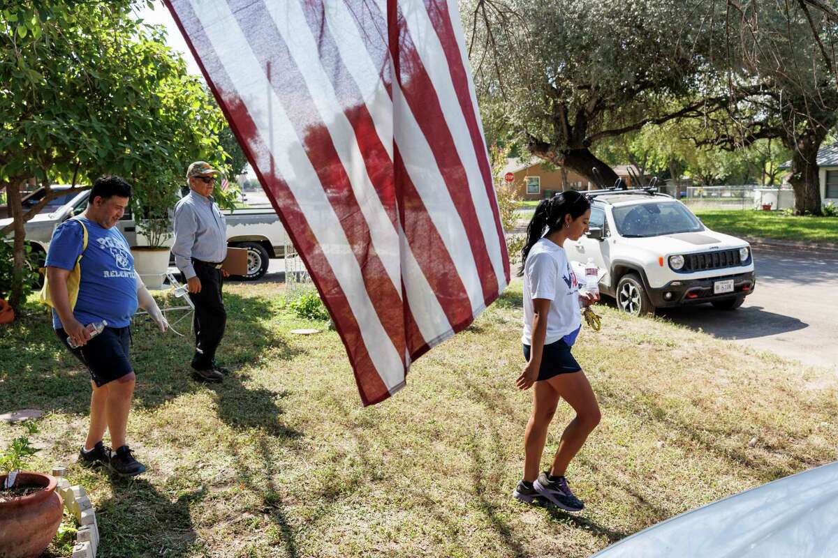 Arnulfo "Arnie" Reyes, from left, Tom Garcia and Kimberly Rubio go door to door in a Uvalde neighborhood as they volunteer in a Get Out the Vote block walk for Beto O'Rourke, the democratic candidate for governor, in Uvalde, Texas, Saturday morning, Oct. 8, 2022. Reyes survived the May 24 shooting at Robb Elementary, but lost 11 of his fourth-grade students, including Rubio’s 10-year-old daughter Lexi.