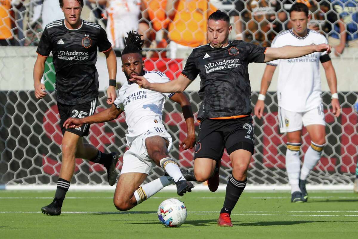 Los Angeles Galaxy forward Raheem Edwards, left, slide tackles in an attempt to get control of the ball from Houston Dynamo forward Sebastián Ferreira (9) during the first half of an MLS soccer match Sunday, Oct. 9, 2022, in Houston.