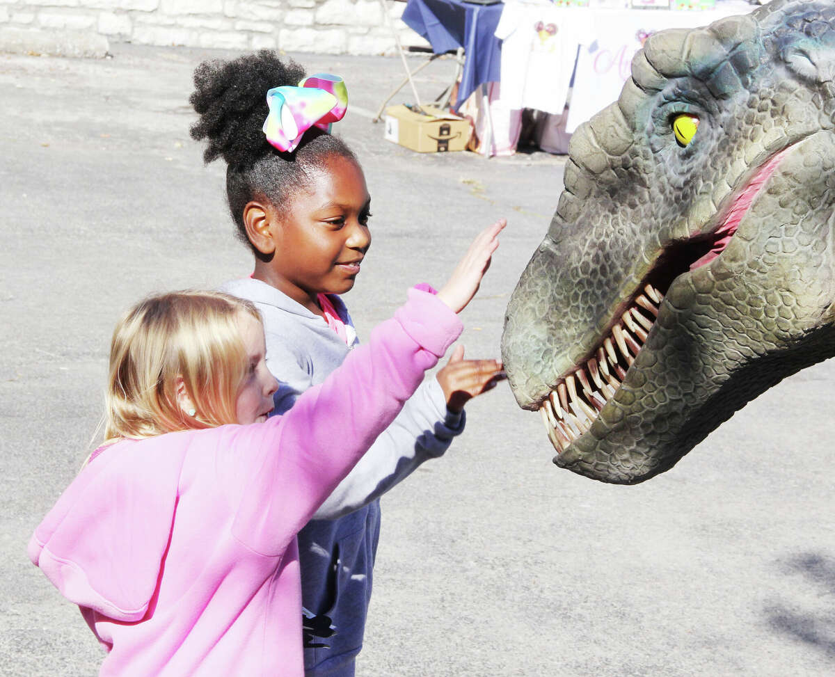 Bella Gleason, 5, left, and Amoriah Gray, 7, pet a Velocaraptor making an appearance at the Hayner Library Local Author Book Fair Saturday at the main library on State Street. The event featured approximately 30 local authors from a variety of genres, as well as showcasing some of the librarie's services. Amoriah was one of the local authors.