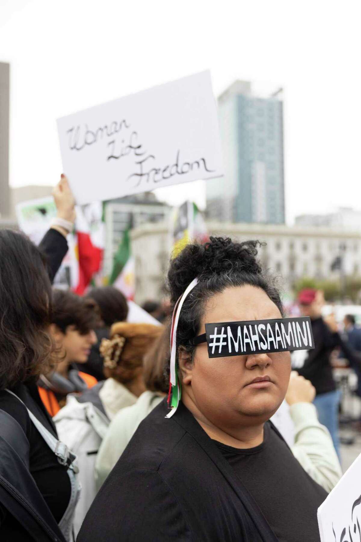 在旧金山市民中心广场举行的支持伊朗人民和反对伊朗政府的集会上，萨纳兹·科斯拉维戴着一副眼镜，上面有一个用来抗议马赫萨·阿米尼之死的标签。