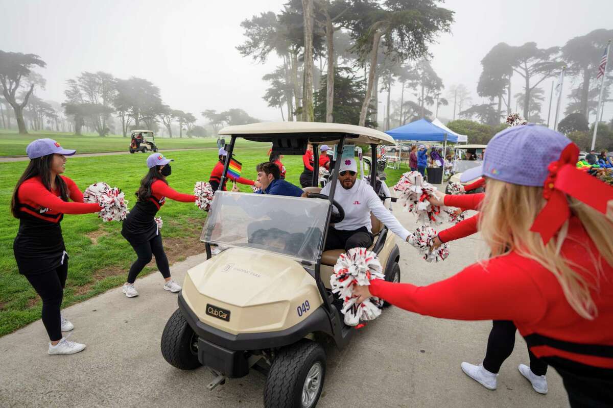 2022年10月8日，加州旧金山，哈丁公园高尔夫球场，第四届旧金山骄傲职业-业余高尔夫锦标赛开始，高尔夫球手们正在通过一队啦啦队。