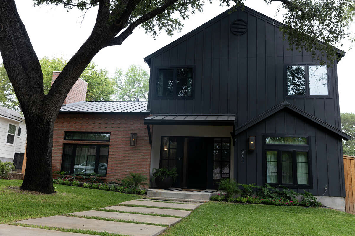 The two-story, near-black portion of a recently constructed home in Alamo Heights is made of fiber cement set off with vertical battans. It contrasts dramatically with the red brick used on the one-story portion.