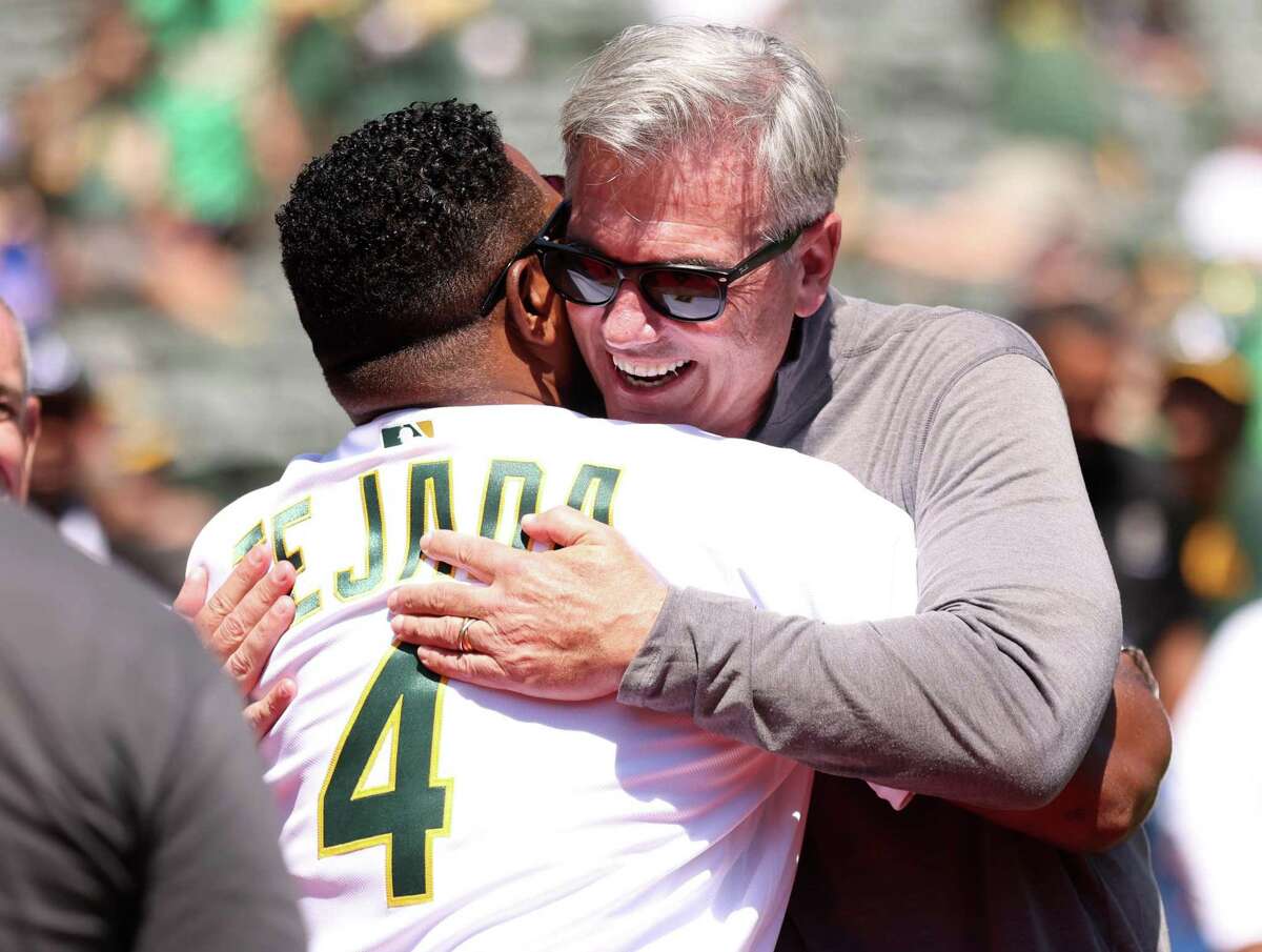 Oakland Athletics’ Billy Beane hugs Miguel Tejada during ceremony honoring 20 game win streak by 2002 A’s before MLB game at Oakland Coliseum in Oakland, Calif., on Sunday, August 28, 2022.