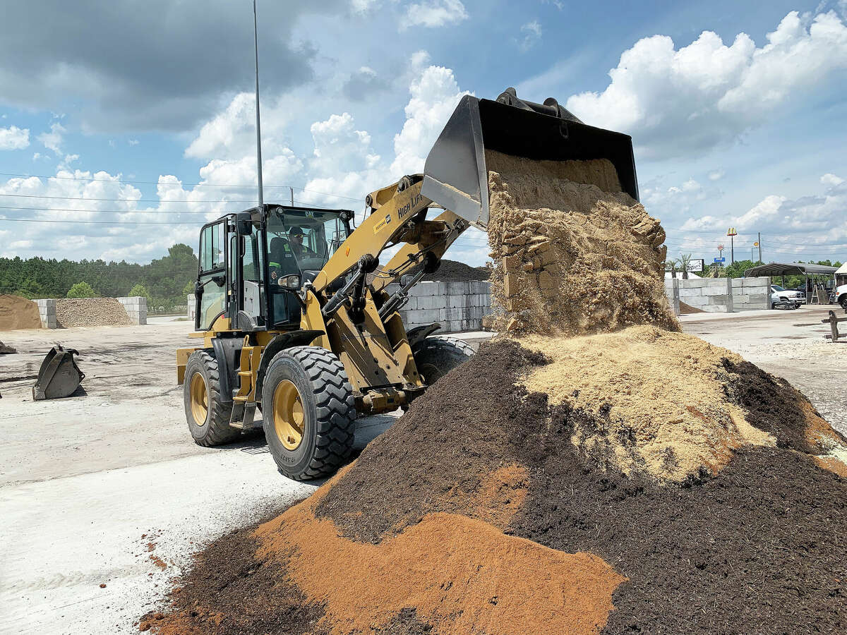 A front-end loader empties another part of a custom mix into the pile on the Heirloom Soils lot in Porter, Texas.
