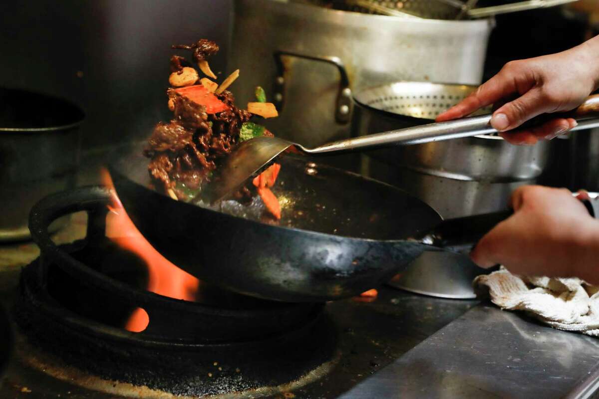 Ding Yong, head chef, prepares Cumin Lamb Stir-Fry at Old Mandarin Islamic Restaurant. Owner Shuai Yang fears that transitioning to electric stoves would be difficult for the restaurant.