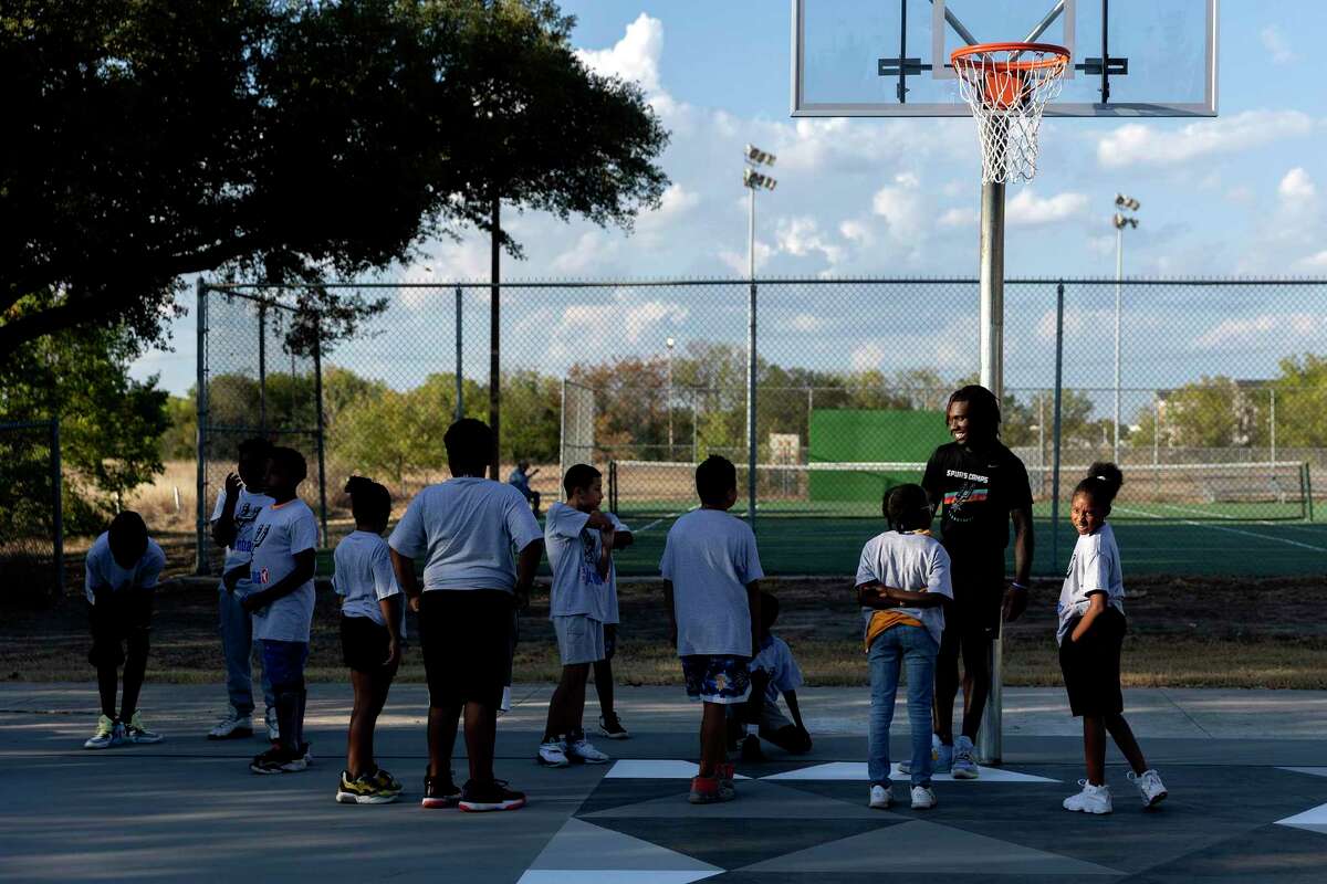 Trey Law, a coach with Spurs Sports Academy, talks with kids at Copernicus Park before running a basketball clinic. The newly renovated court is the 10th court that has been built or renovated by the Spurs in an effort to provide safe places for kids to play.