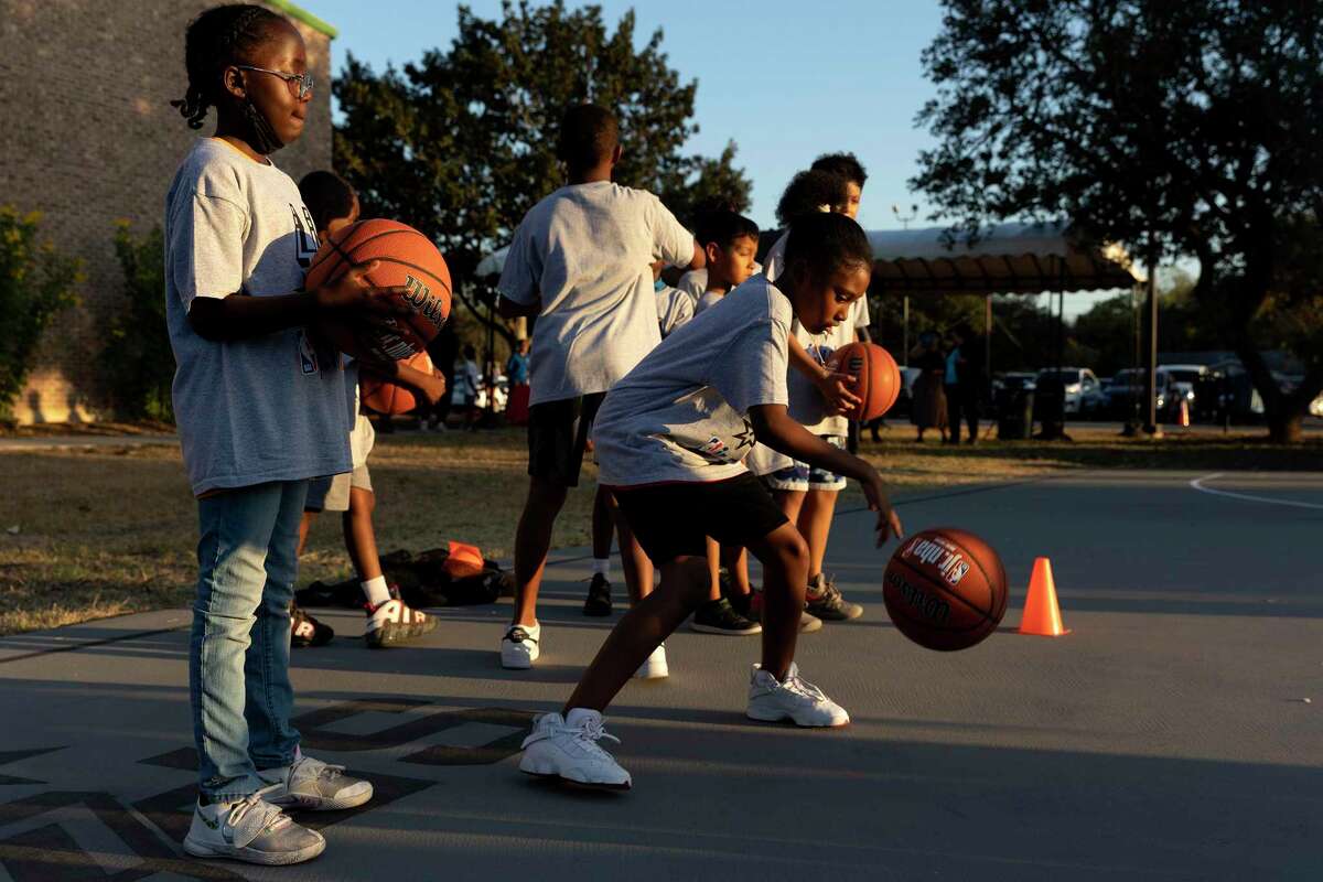 Aunjeo Perry, 10, and Anayah Pickens, 9, work on their dribbling skills at a clinic hosted by Spurs Sports Academy at Copernicus Park. The court is the 10th that has been built or renovated by the Spurs in an effort to provide safe places for kids to play.