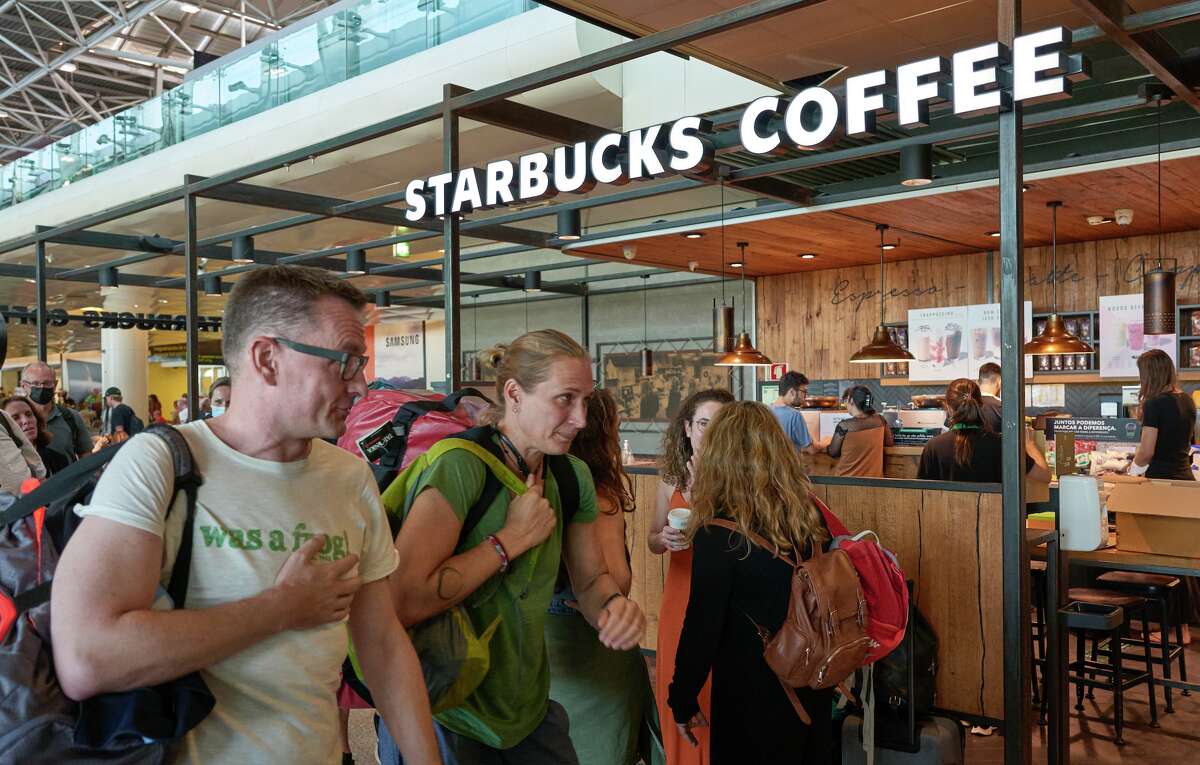 Tourists walk past a Starbucks cafe at Humberto Delgado International Airport in June 2022 in Lisbon, Portugal.