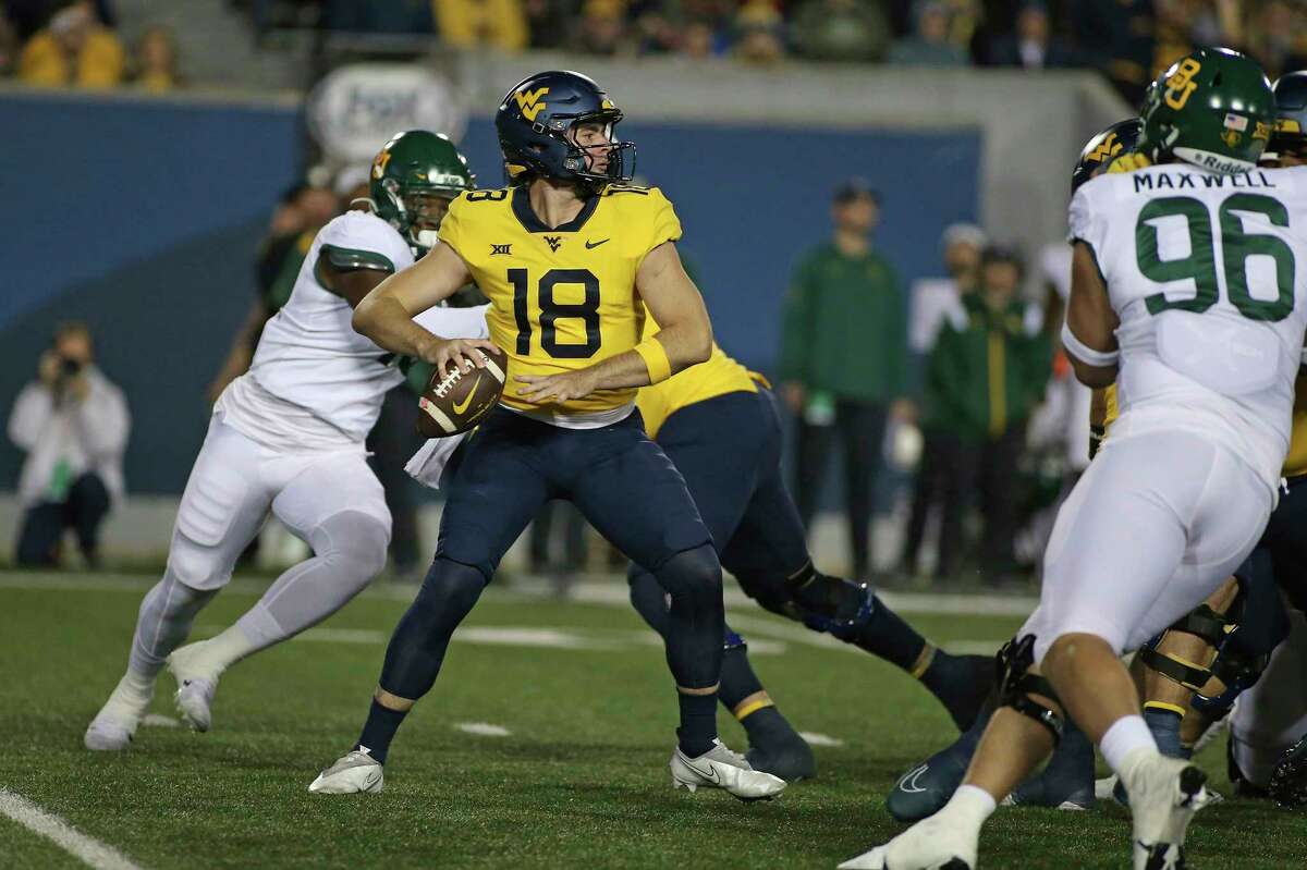West Virginia quarterback JT Daniels (18) looks for a receiver during the first half of the team's NCAA college football game against Baylor in Morgantown, W.Va., Thursday, Oct. 13, 2022.
