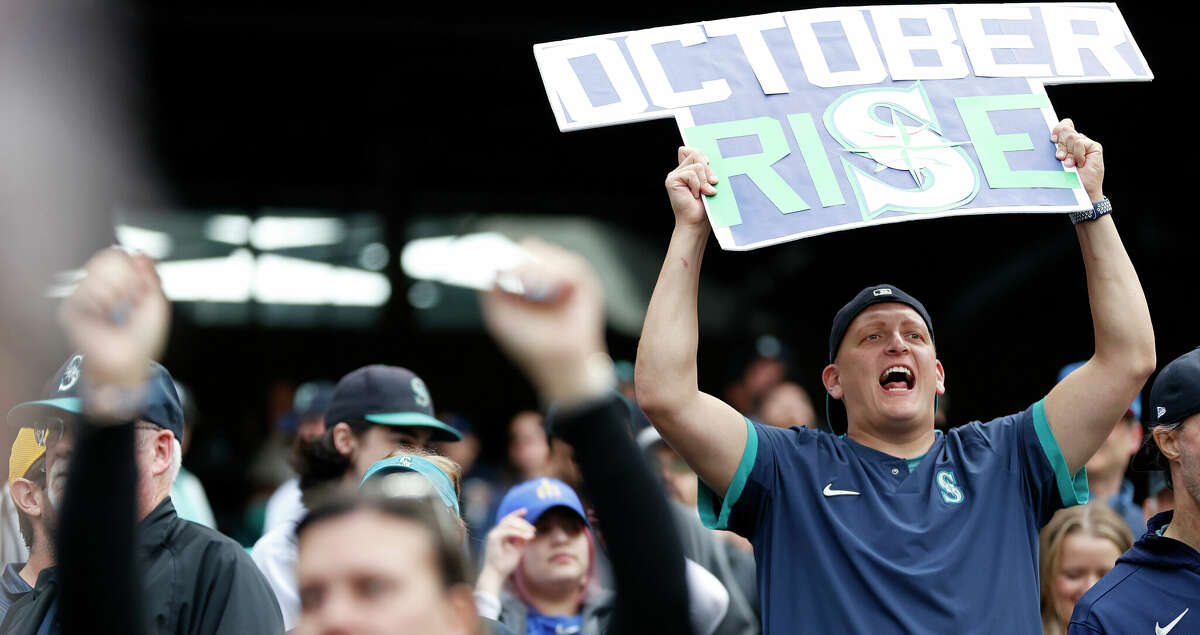 Fans hold signs during the ninth inning between the Seattle Mariners and the Detroit Tigers at T-Mobile Park on October 05, 2022 in Seattle, Washington. (Photo by Steph Chambers/Getty Images)