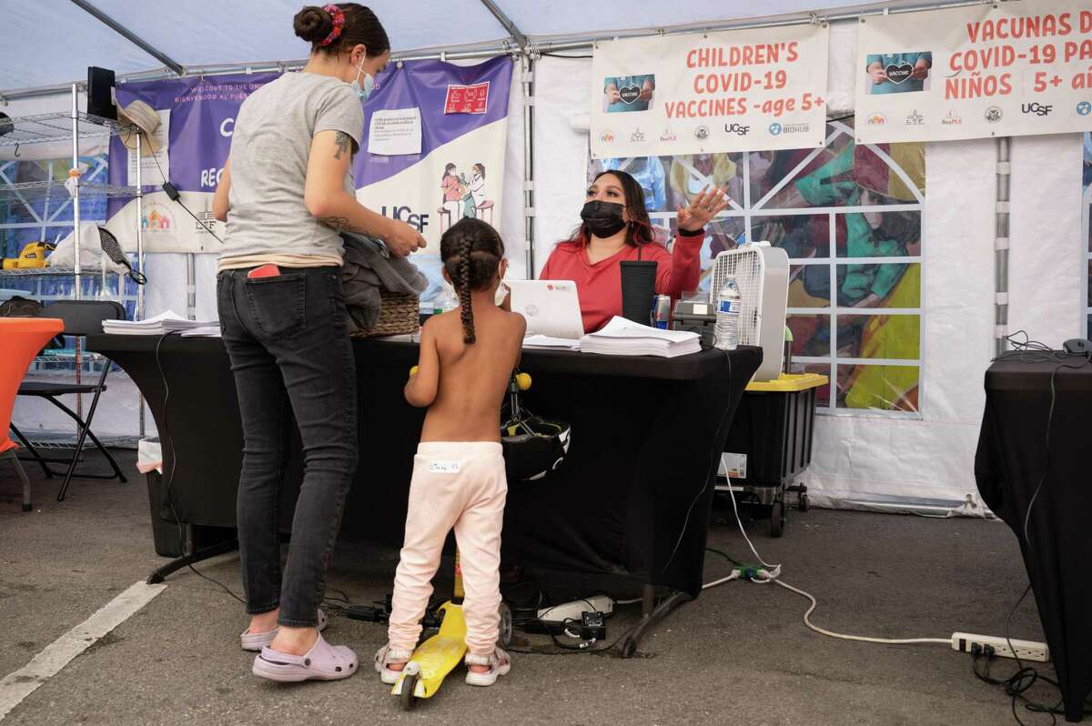 A mother brings her child to get a vaccination at the United in Health/Unidos en Salud COVID-19 testing and vaccination clinic in San Francisco on Sept. 23, 2022.