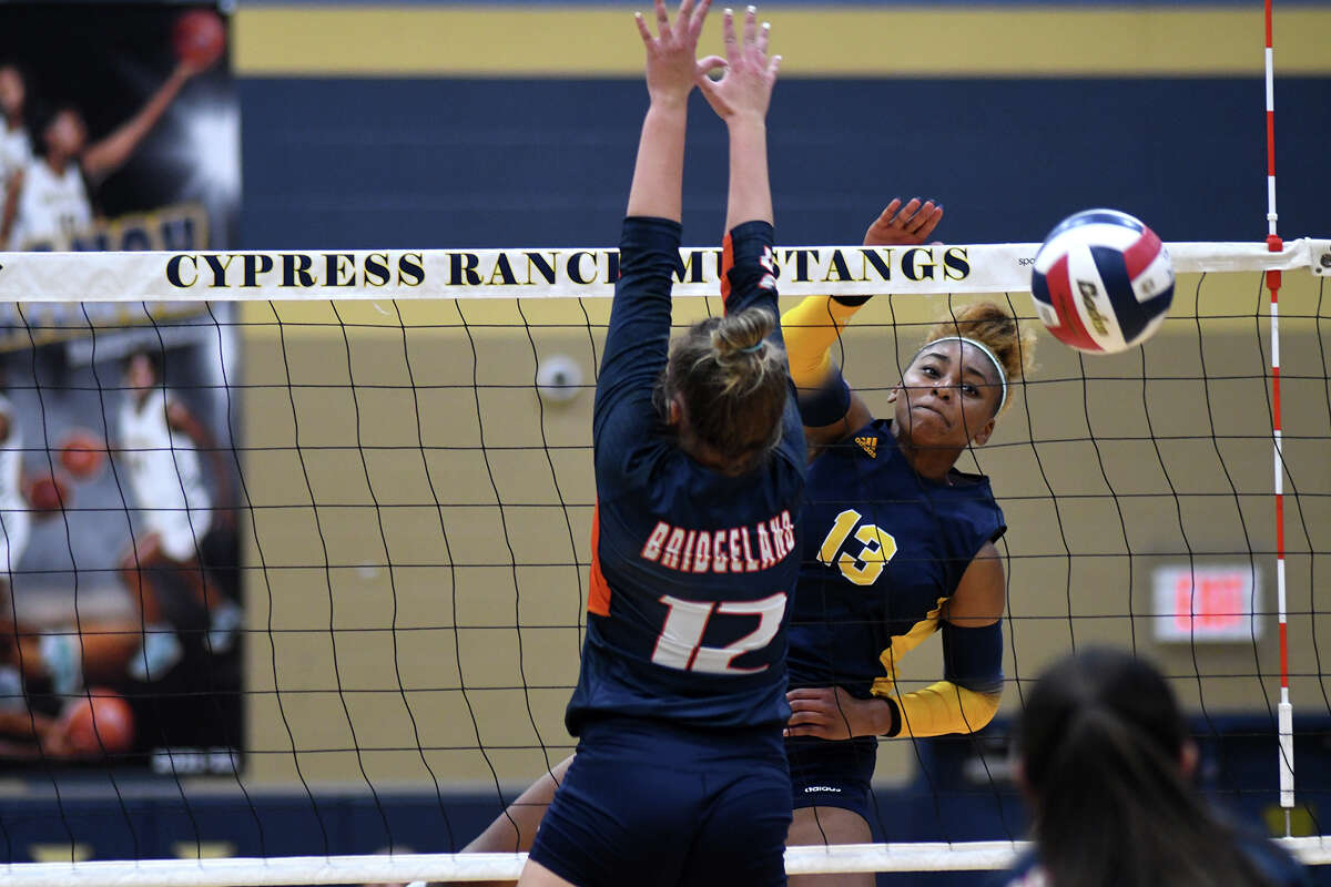 Cy-Ranch senior outside hitter Bianna Muoneke (13) finishes a kill against Bridgeland senior outside hitter Olivia Waggoner (12) during the first set of their round two district matchup at Cy Ranch High School on Oct. 14, 2022.