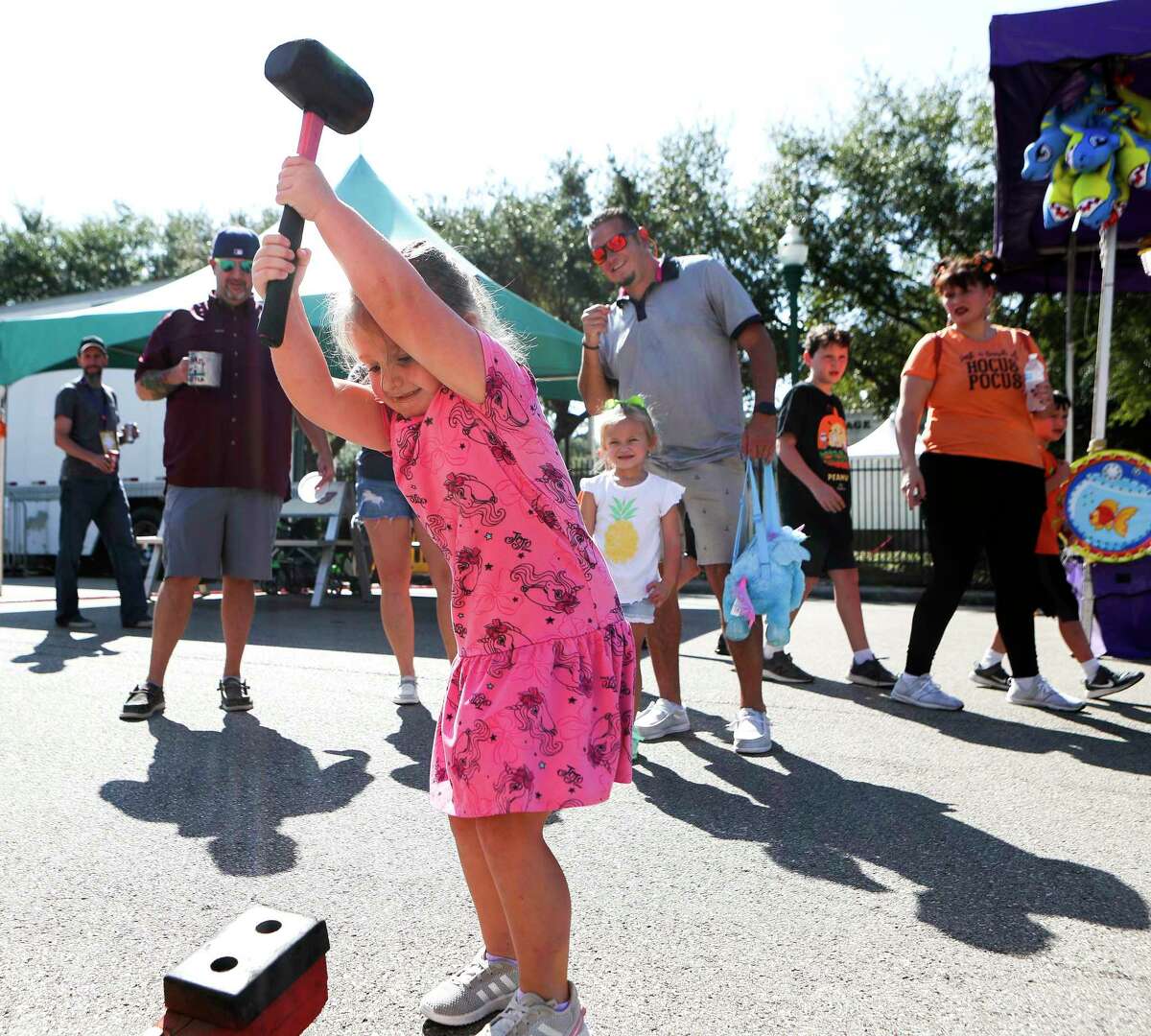 Fallon Hartsell tries her hand and ringing a bell with a hammer during the annual Conroe Cajun Catfish Festival, Saturday, Oct. 15, 2022, in Conroe.