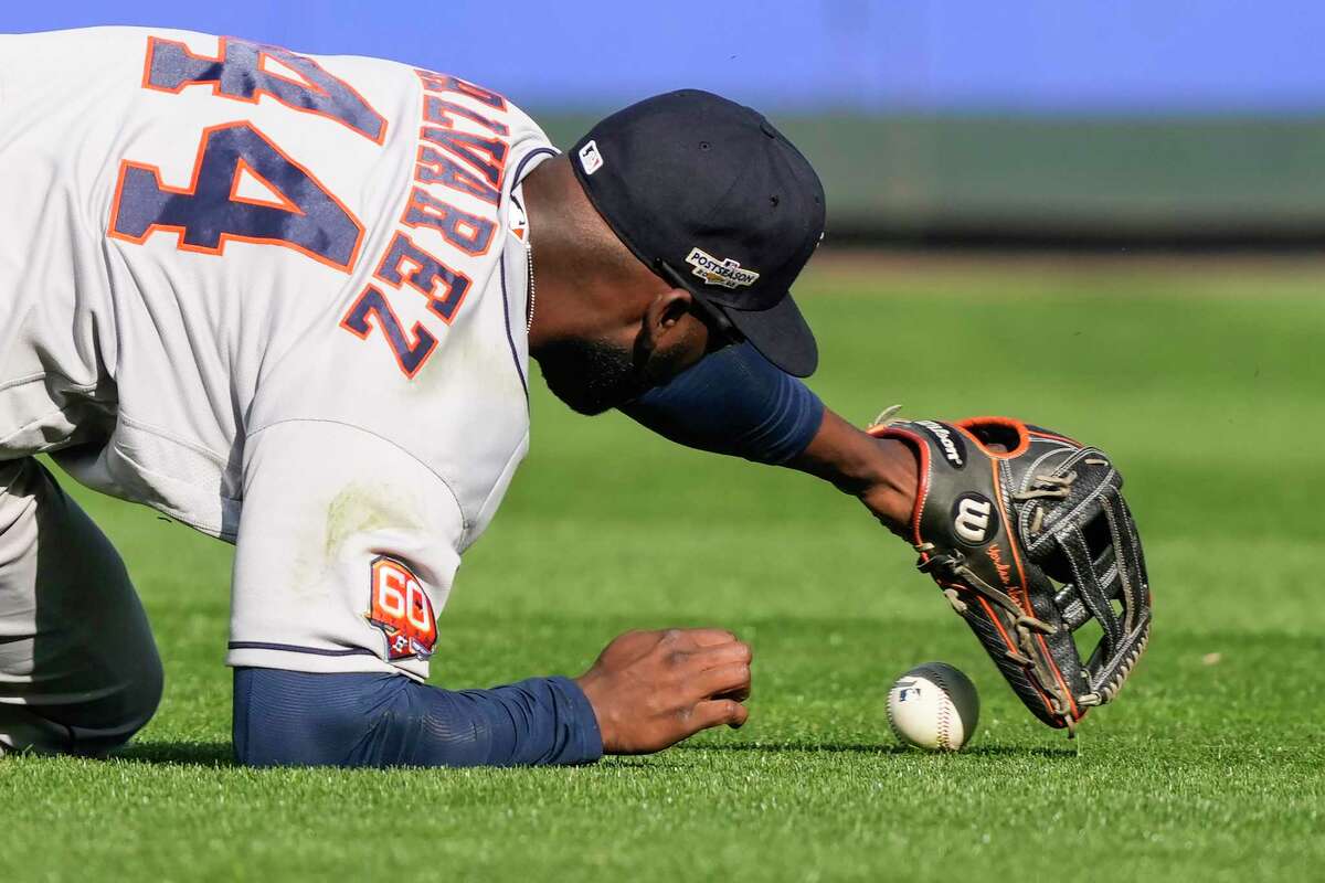 Houston Astros left fielder Yordan Alvarez picks up the baseball after failing to come up with the catch on a looping single by Seattle Mariners shortstop J.P. Crawford during the fifth inning of Game 3 of the American League Division Series on Saturday, Oct. 15, 2022, in Seattle.