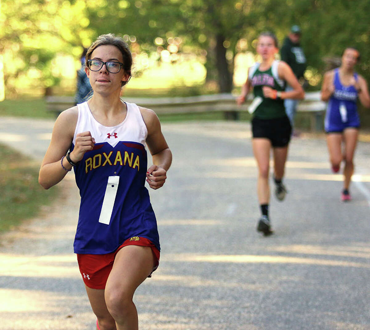 Roxana's Raelee Kimbro (left) runs midway through the race Saturday morning in the Cahokia Conference cross country meet at Bryan Memorial Park in Salem.