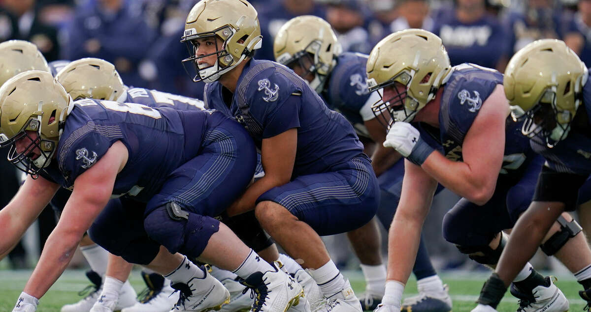 Navy quarterback Tai Lavatai, center, prepares for the snap during the first half of an NCAA college football game between Navy and Tulsa, Saturday, Oct. 8, 2022, in Annapolis, Md. Navy won 53-21. (AP Photo/Julio Cortez)