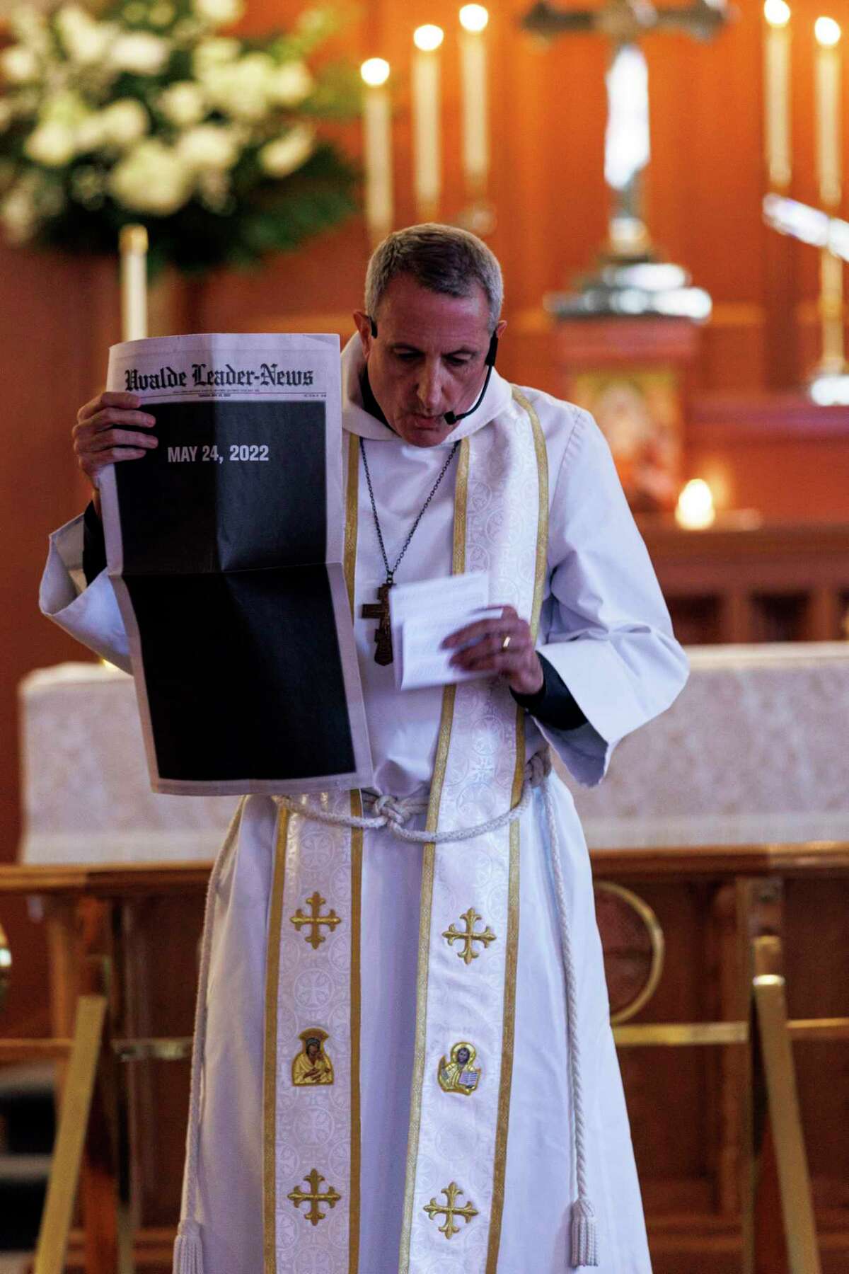The Rev. Michael K. Marsh holds up a copy of the Uvalde Leader-News during a prayer service at St. Philip’s Episcopal Church in Uvalde two days after the May 24 massacre of 21 people at Robb Elementary School.