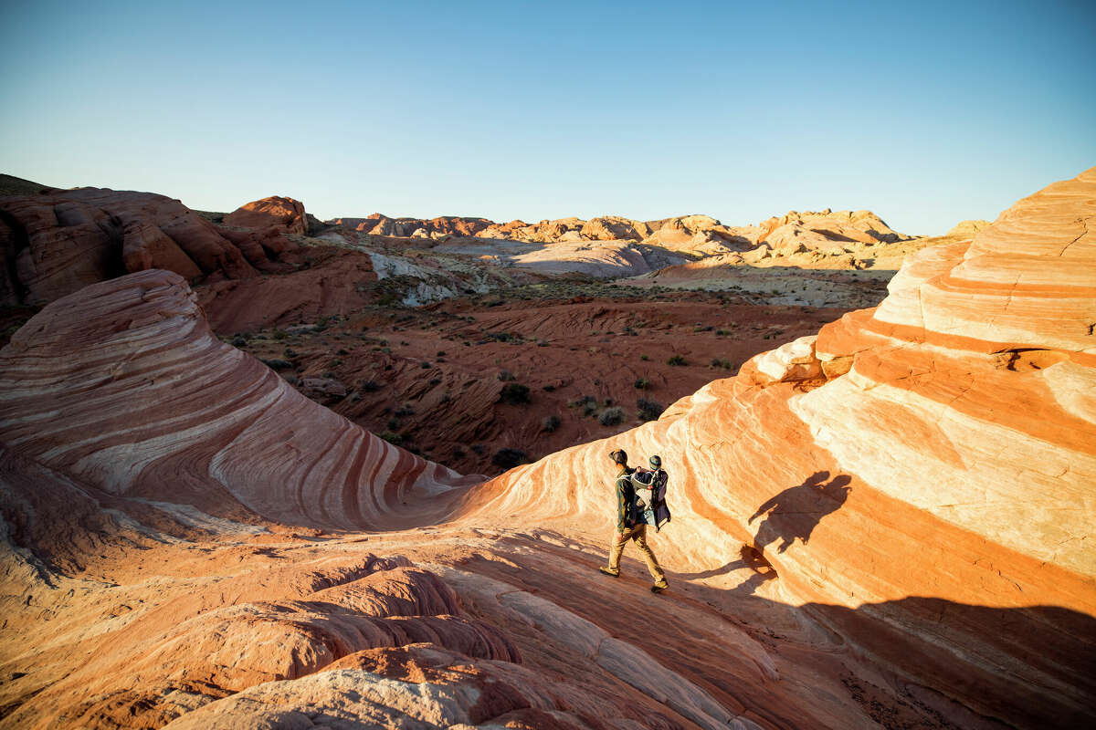 A man and his son hike in the red rocky desert landscape of Valley of Fire State Park outside of Las Vegas, Nevada. 