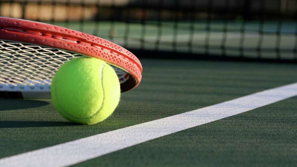 Tennis racket lying on a tennis ball near the net and court line