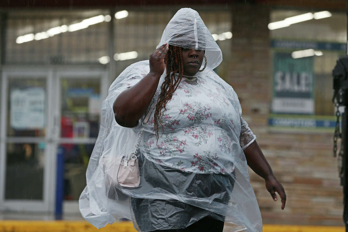 Shameka McCorkle shields herself from the rains as she walks to a bus stop on her way to work on Monday, Oct. 17, 2022. 