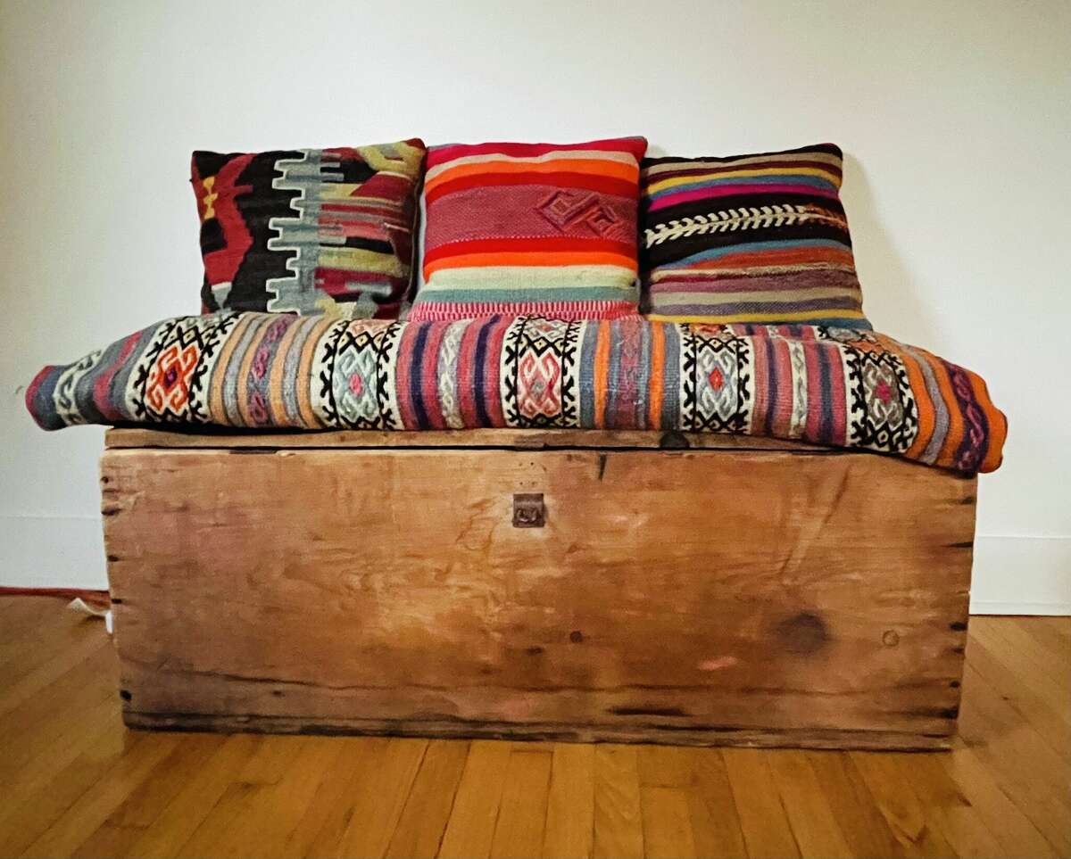 A primitive trunk transformed into a lounge area with the author's pillows, bought on Facebook Marketplace.