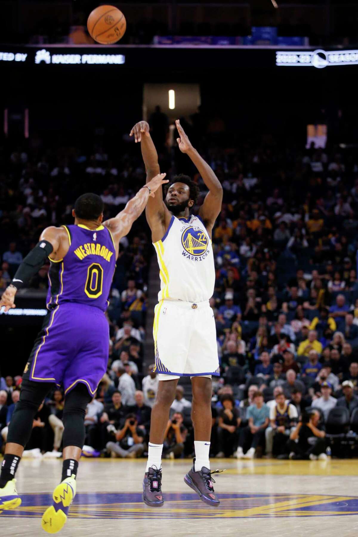 Golden State Warriors forward Andrew Wiggins (22) attempts a three pointer against Los Angeles Lakers guard Russell Westbrook (0) in the fourth quarter of an NBA game at Chase Center in San Francisco, Calif., Tuesday, Oct. 18, 2022. The Warriors won 123-109 in their home opener.
