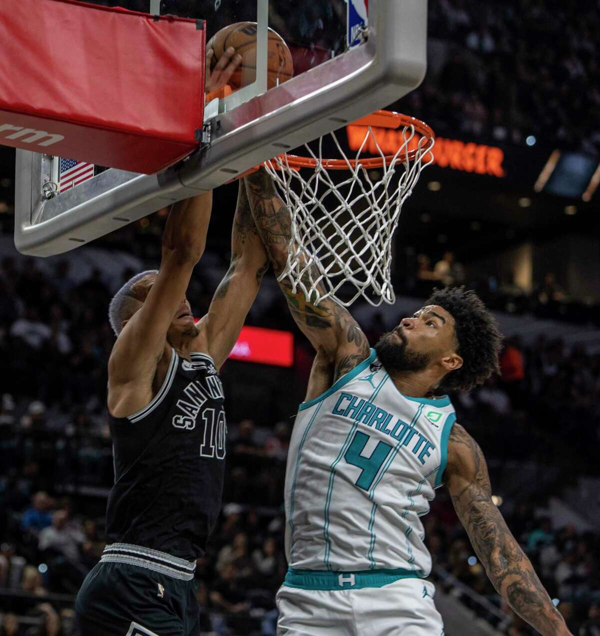 Charlotte Hornets center Nick Richards fouls San Antonio Spurs forward Jeremy Sochan Wednesday night, Oct. 19, 2022, in the AT&T Center as Sochan goes for a dunk during their regular season opening night matchup.