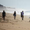 People stroll along Half Moon Bay beach enjoying the warm temperatures in Half Moon Bay, Calif. on Oct. 19, 2022.