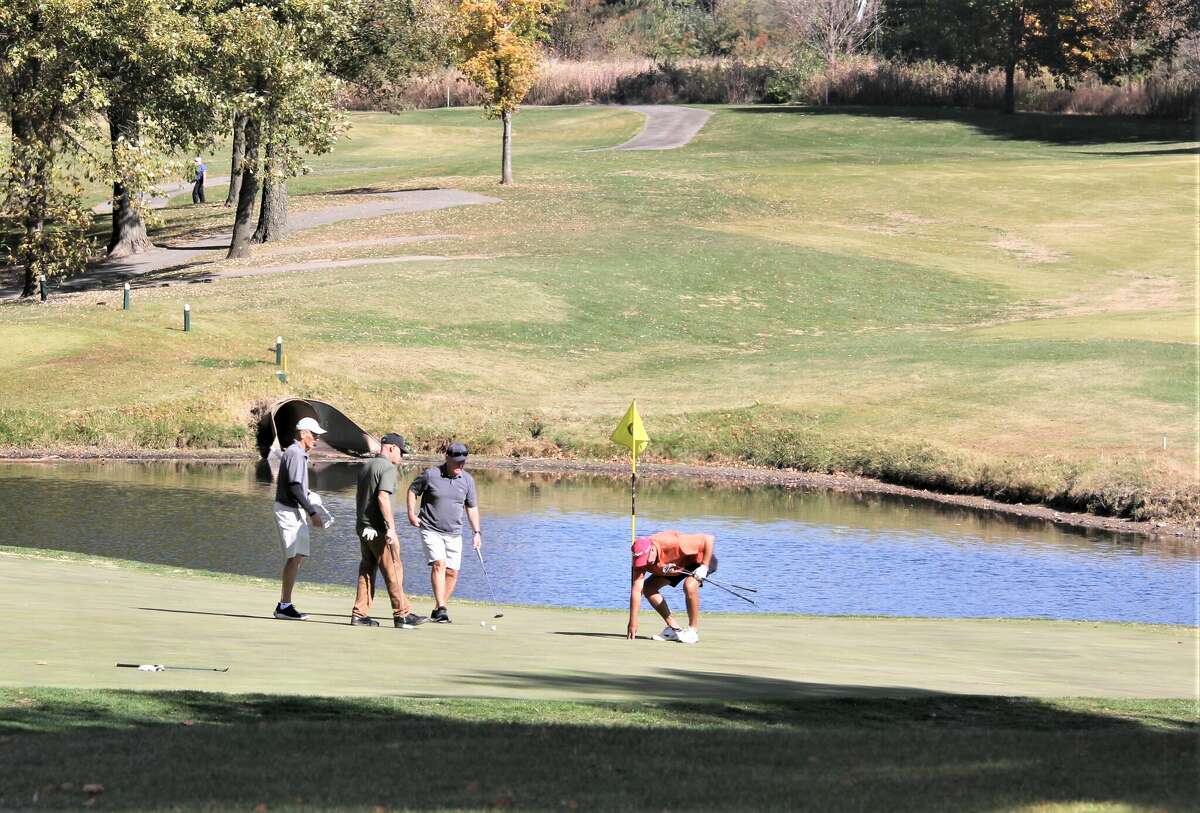 A golfer retrieves his ball after sinking a putt at the Spencer T. Olin Golf Course in Alton late Friday morning. Temperatures reaching into the 70s made it a good day to get outside for those who were able.