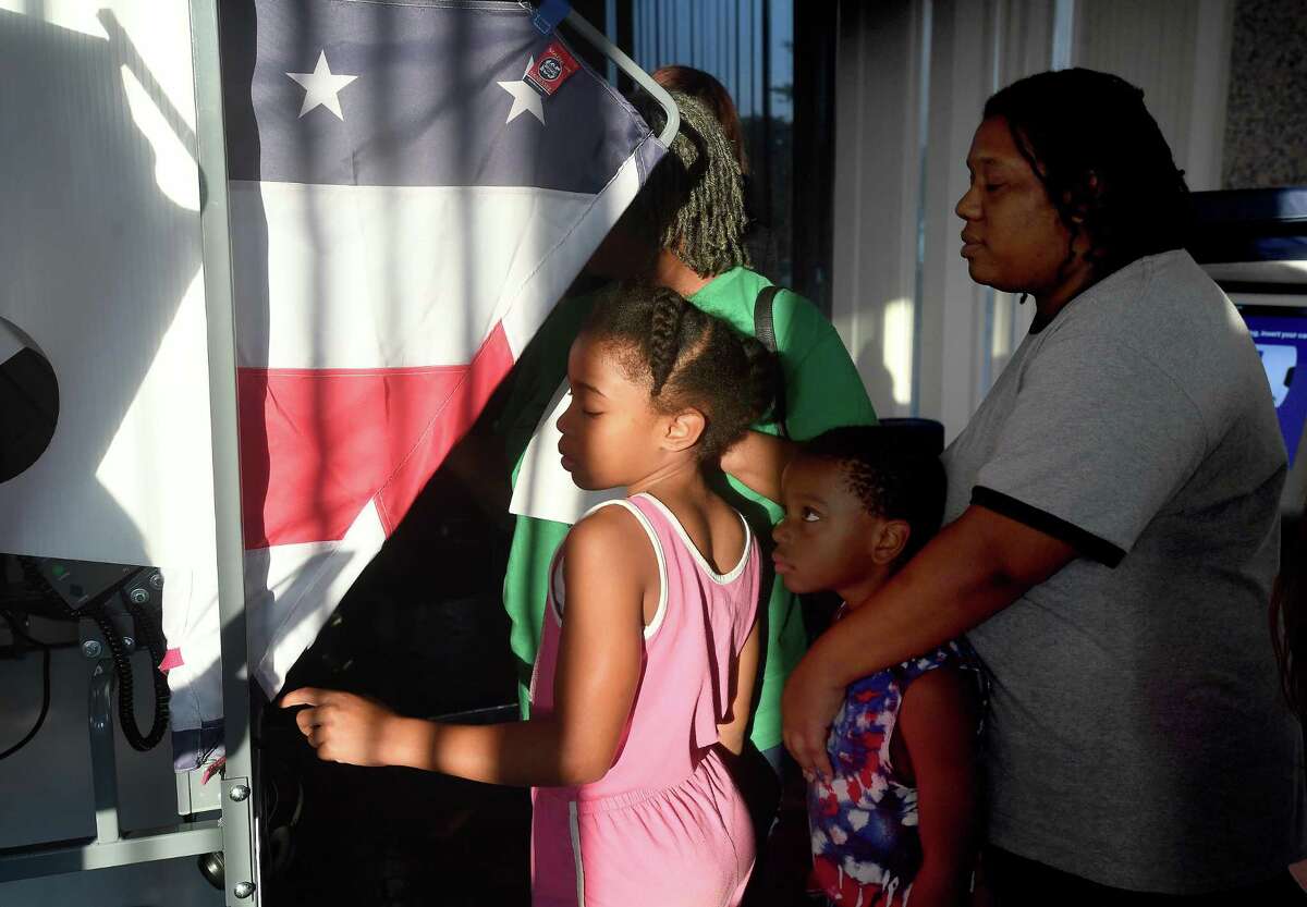 Marie Riley, brother Louis Palmer and their mother Nakia Riley watch as great-grandmother Ella Riley tries out Jefferson County's new ESS voting machines during a forum held Thursday in the Jefferson County Courthouse. Photo made Thursday, October 13, 2022 Kim Brent/Beaumont Enterprise