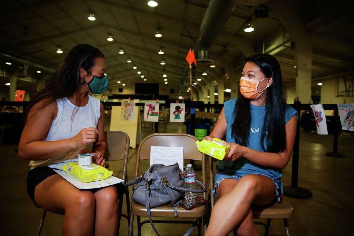 Jessie Ho (left) of Fremont and Megan Wong of San Jose chat receiving their second Pfizer boosters at the Santa Clara County Fairgrounds in September.