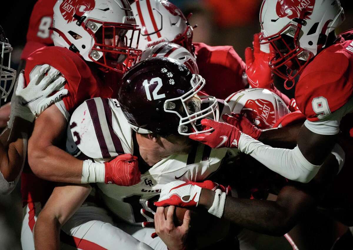 Cinco Ranch Cougars quarterback Gavin Rutherford (12) gets tackles by a mass of Katy Tigers defensive players during the second half of a high school football game Friday, Oct. 21, 2022, at Rhodes Stadium in Katy.