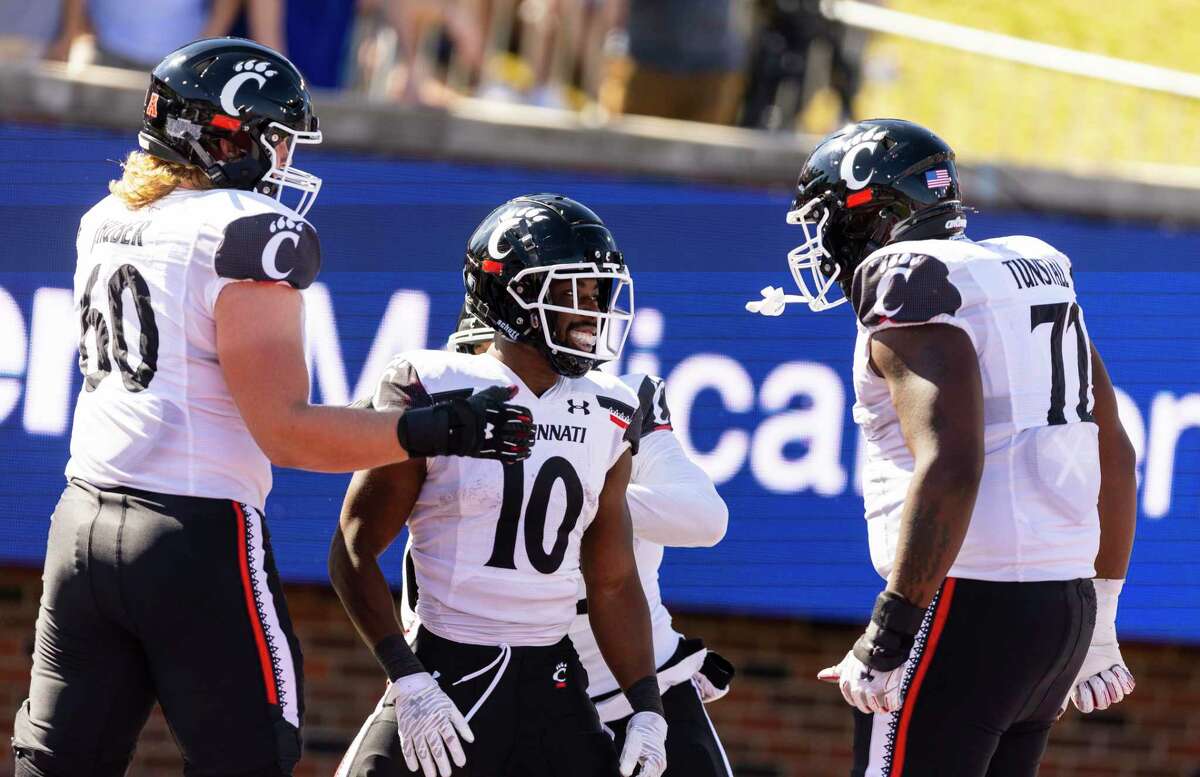 Cincinnati running back Charles McClelland (10) is congratulated by offensive linemen Joe Huber (60) and James Tunstall (72) after scoring a touchdown during the first half of an NCAA college football game against SMU, Saturday, Oct. 22, 2022, in Dallas.